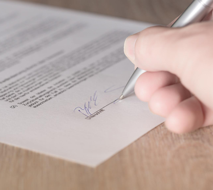 A hand holding a silver pen signing an ABA for autism petition.