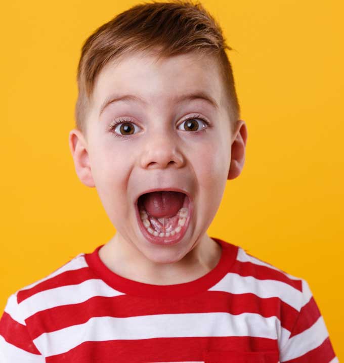 A child wearing a red and white striped shirt with his eyes and mouth wide open in front of an orange background