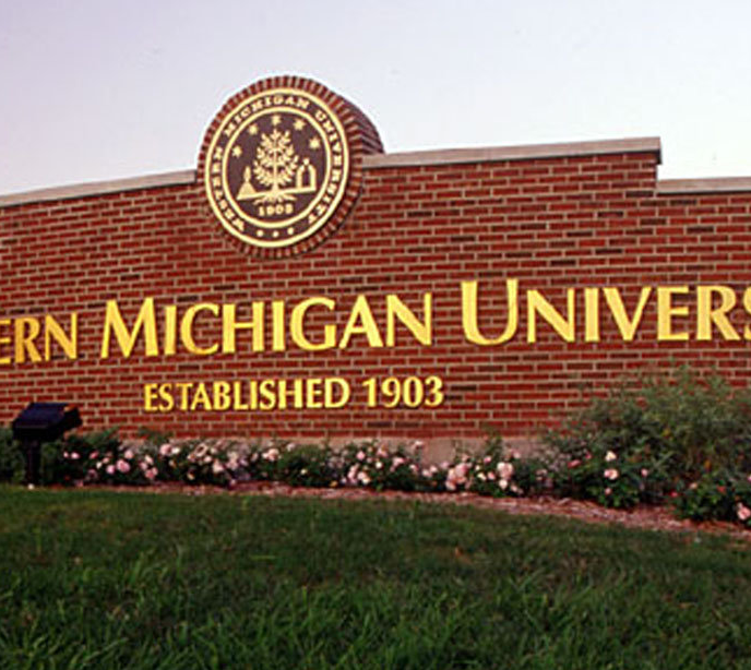 A cropped shot of a brick wall with gold text for the Western Michigan University established in 1903 on grass.