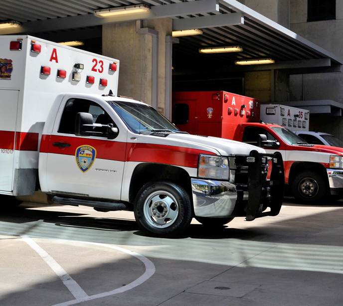 Three red and white fire trucks parked in a row in a parking lot.