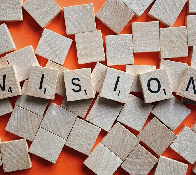 Scrabble wooden letters spelling the word vision on top of lots of blank scrabble wooden blocks.