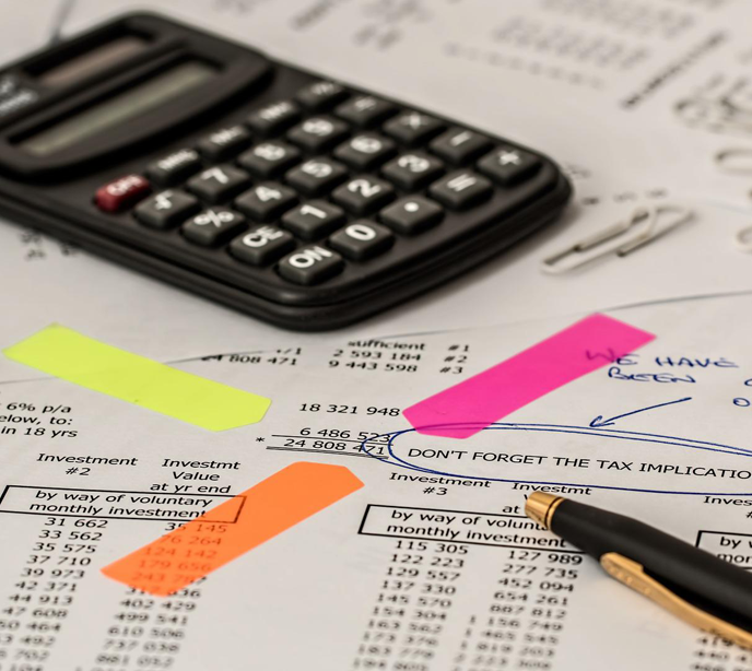 A calculator on sheets of paper displaying text investment numbers with three highlighted sticky notes.