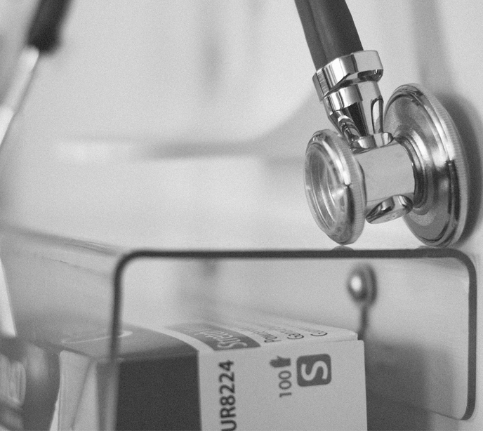 A black & white stethoscope above a medical glove box.