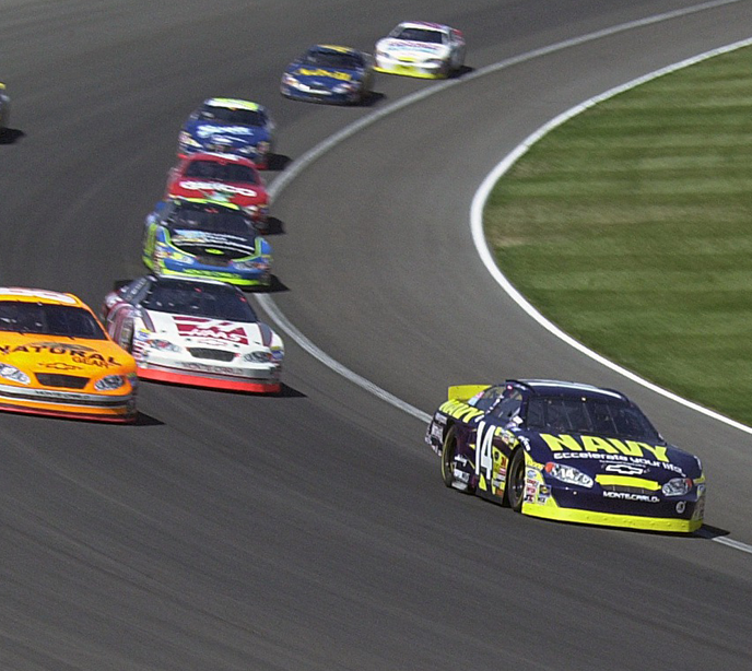 Nine cars racing around a bend on a track.