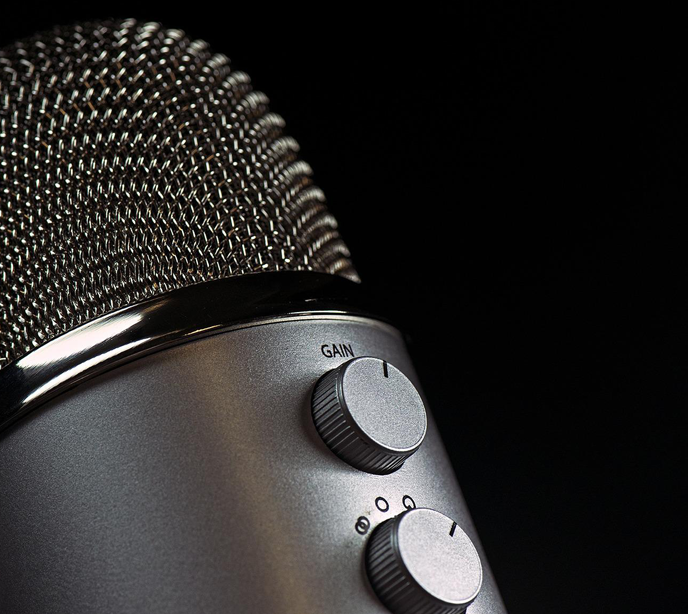 A close-up shot of a silver microphone on a black background.