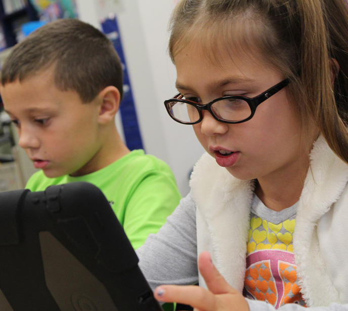 Two children looking at tablets.