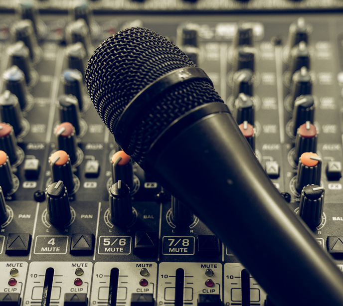 A wireless black microphone placed diagonally across a sound panel with dials in different colors