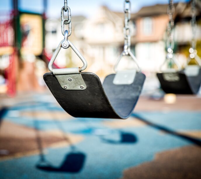 A close-up shot of two swings in a play park.