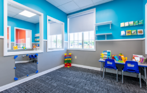 A therapy room at Lighthouse Autism Center with blue and gray walls, a table with two blue chairs and a window