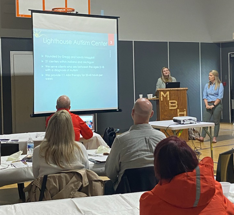 A presentation about Lighthouse Autism Center being observed by four audience members.