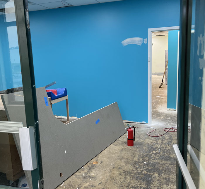 A view through an open glass door into a room with bright blue walls and an L-shaped piece of wood with a small fire hydrant