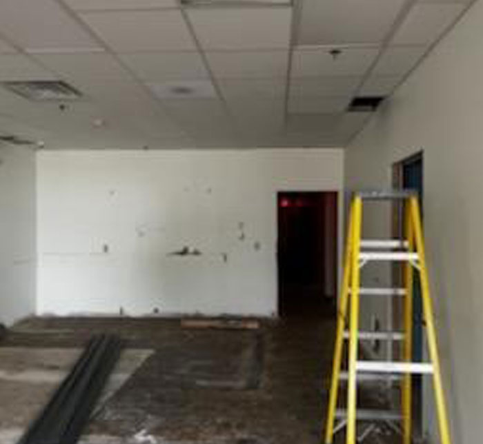 A gray room at Lighthouse Autism Center being renovated with a yellow step ladder and rubber on the floor