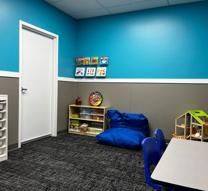 A Kalamazoo East Autism Center therapy room with a blue and gray wall, a table and books with toys
