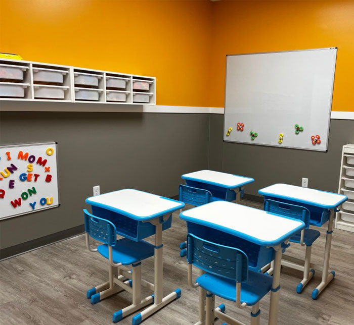 A therapy room with desks and a whiteboard for pre-adacemic learning and school readiness at Lighthouse Autism Center