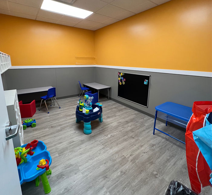 A therapy room at Kalamazoo East Center with a yellow and gray wall, tables and toys