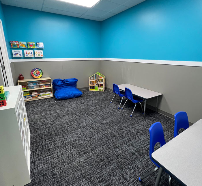 A therapy room at Kalamazoo East Center with a gray and blue wall, tables and white drawers