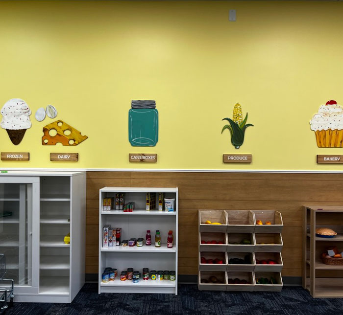 A therapy room at Kalamazoo East Center with a yellow and wooden wall and shelves with toy food products
