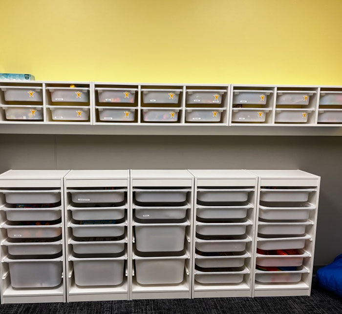 Two shelving units in the center of a therapy room at Kalamazoo East Center in front of a yellow wall