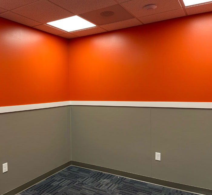 A brightly lit empty therapy room with a gray and orange walls at Lighthouse Autism Center