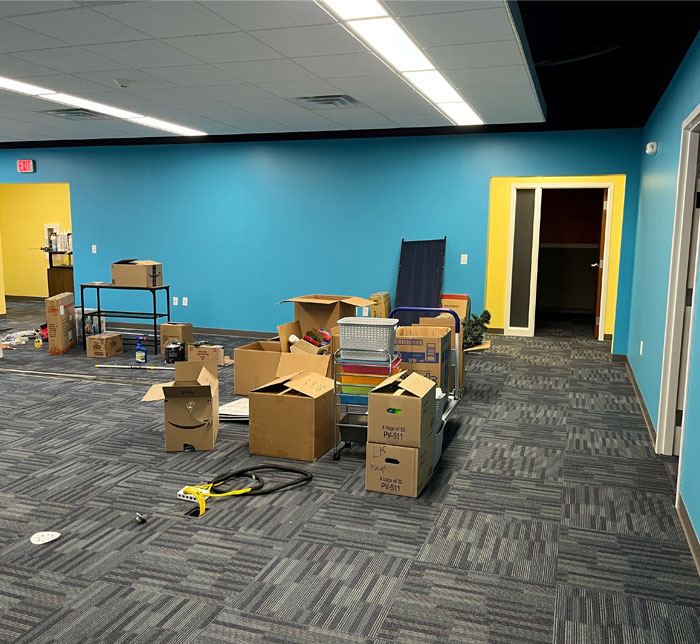 A playroom being renovated with cardboard boxes on the floor and a blue wall at Lighthouse Autism Center