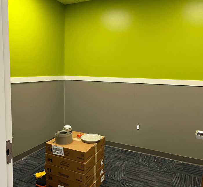 A newly renovated therapy room with a green and gray wall and five cardboard boxes stacked with gray tape at LAC South Bend