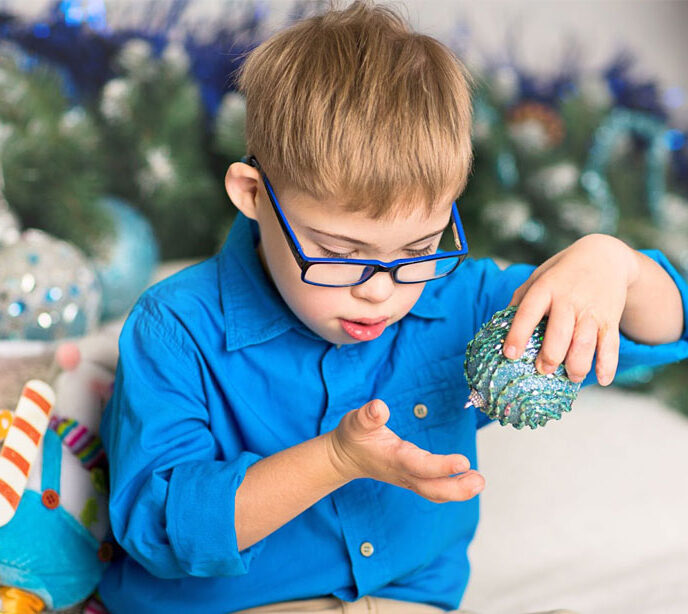 A child wearing a blue shirt holding a blue christmas decoration