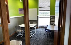 An intraverbal/vocabulary developement room at the East Moline center with a green wall, whiteboard and a tall window open