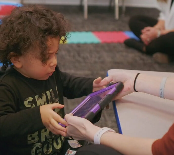 A child being handed a purple tablet