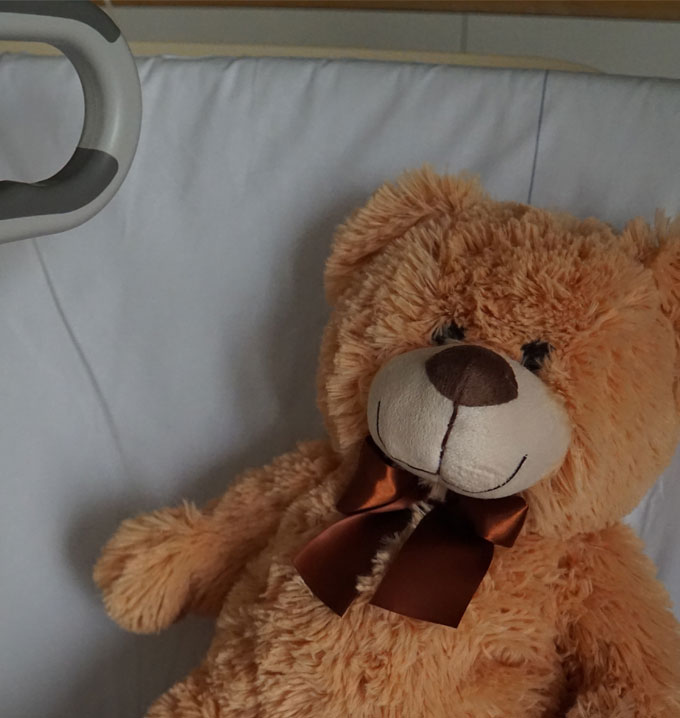 A teddy bear laying on a white pillow.