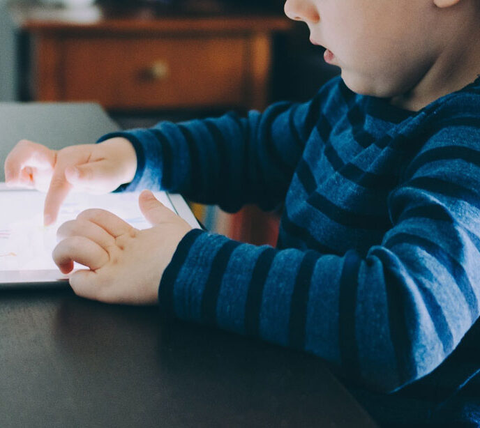 A child sat at a table playing on a tablet