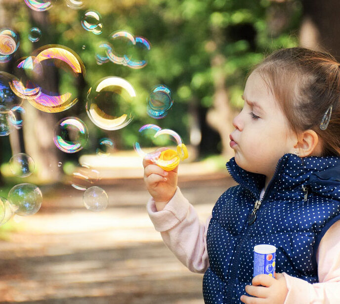 A child outside blowing bubbles