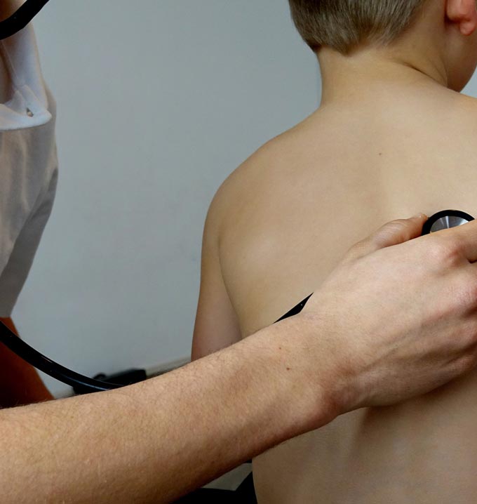 A medical professional holding a stethoscope on a child's back