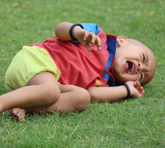 A child laying on the grass crying