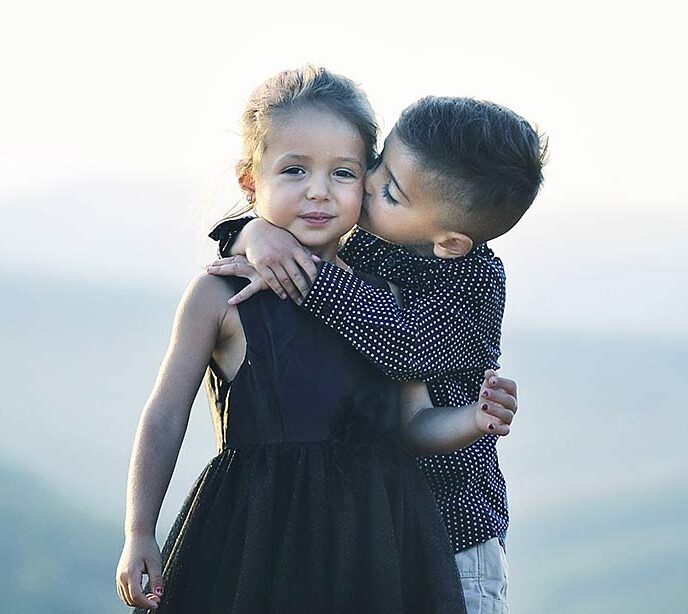 Two sibling children one boy and a girl hugging and embracing
