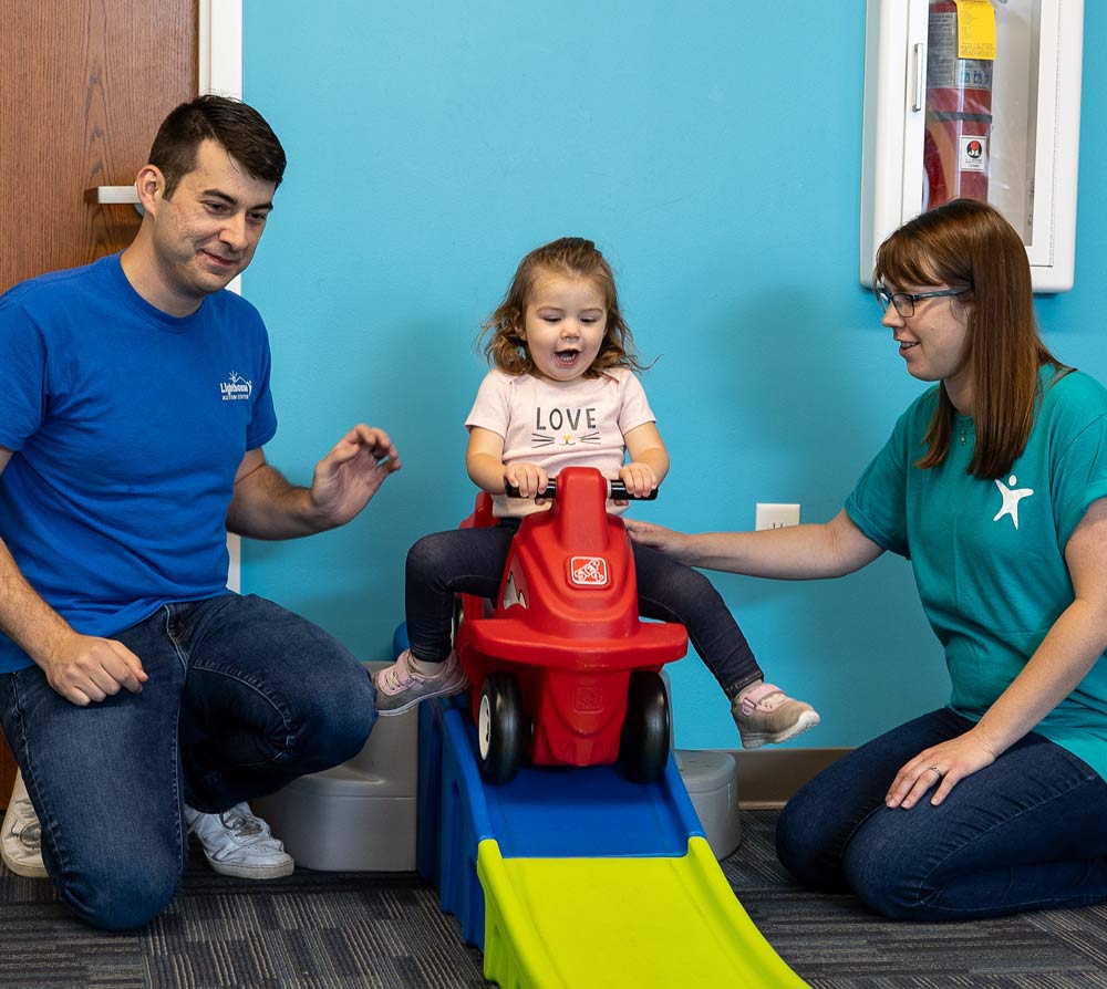 Therapy room at Lighthouse Autism Center with toys on a table with blue chairs and book shelves above