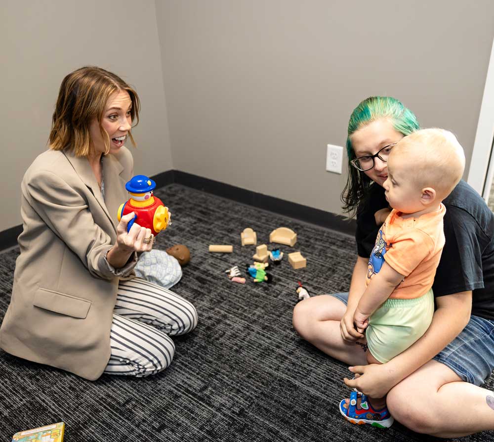 Therapy room at Lighthouse Autism Center with toys on a table with blue chairs and book shelves above